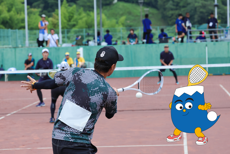 ソフトテニスの試合でボールを打ち返す選手