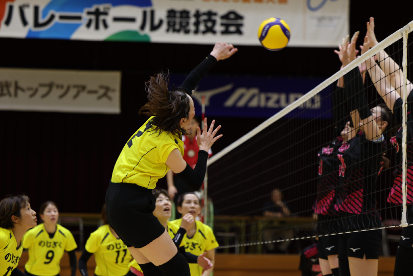 バレーボールの試合でスパイクを打つ女子選手