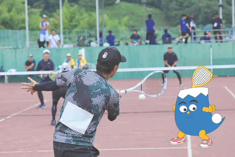 ソフトテニスの試合でボールを打ち返す選手