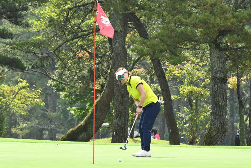 グリーン上でパットを打つ女子選手